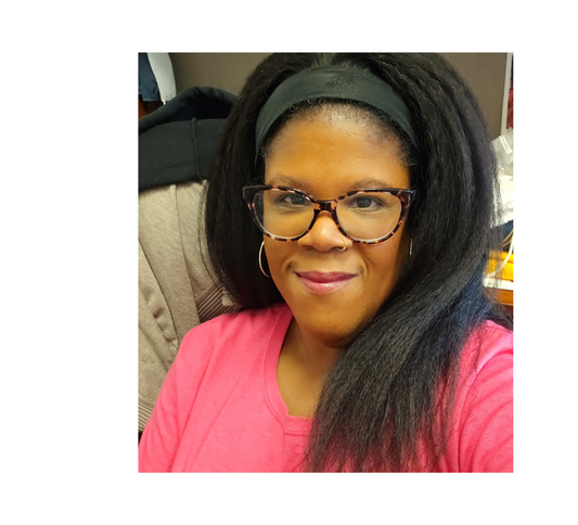 African American woman with shoulder length, long black hair.  She is sitting in a high back chair.  She is wearing a dark pink shirt and is smiling.